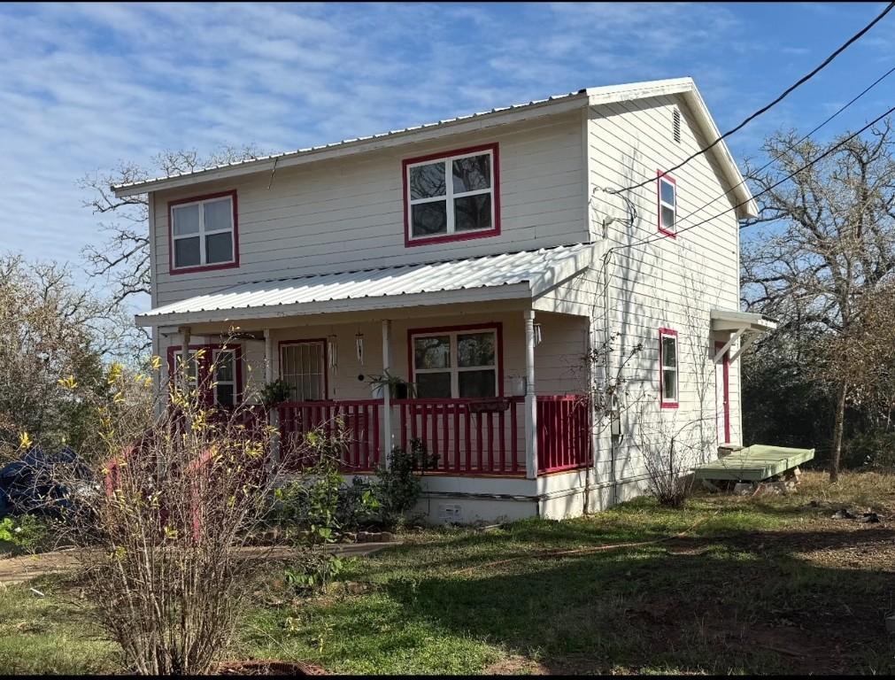 front facade featuring covered porch and a front yard