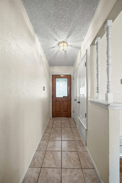 doorway with light tile patterned flooring and a textured ceiling