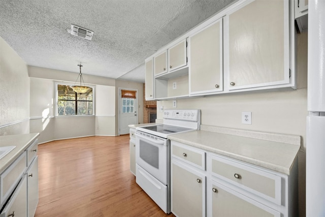 kitchen featuring electric range, hanging light fixtures, a textured ceiling, and light hardwood / wood-style floors