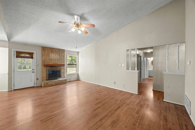 unfurnished living room with a textured ceiling, ceiling fan, hardwood / wood-style flooring, and a brick fireplace