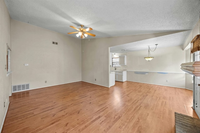 unfurnished living room with a textured ceiling, ceiling fan, lofted ceiling, and light wood-type flooring