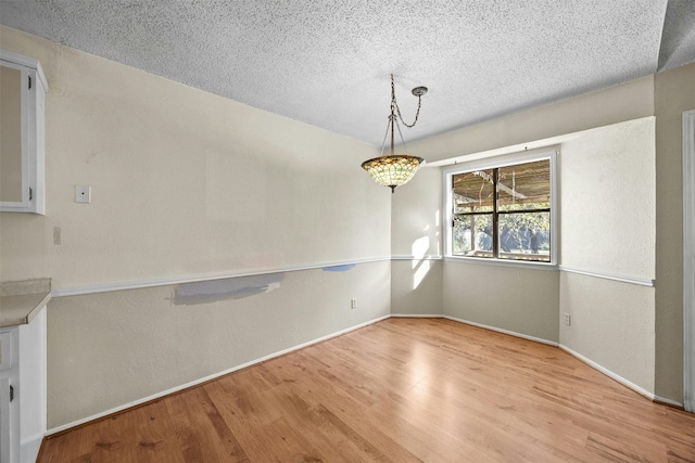 unfurnished dining area featuring light hardwood / wood-style flooring and a textured ceiling