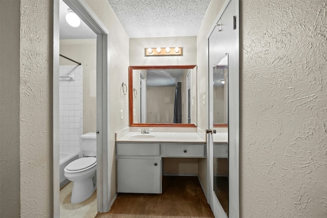 full bathroom with tiled shower / bath combo, wood-type flooring, a textured ceiling, toilet, and vanity