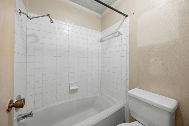 bathroom with tiled shower / bath, a textured ceiling, and toilet