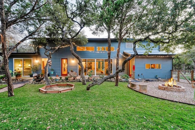 rear view of house with a fire pit, fence, and a lawn