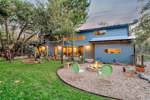 back house at dusk featuring a fire pit and a yard