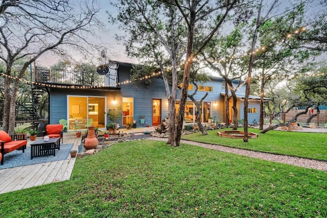 back house at dusk featuring a lawn, a patio area, and an outdoor living space