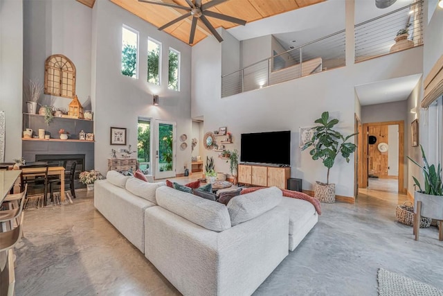 living room featuring ceiling fan, a wealth of natural light, wooden ceiling, and a high ceiling