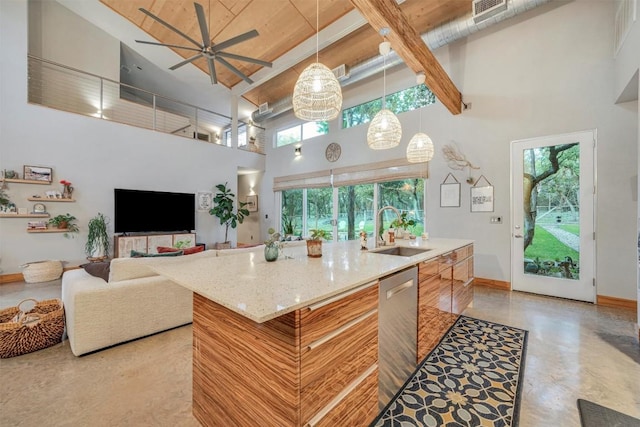 kitchen featuring dishwasher, a center island with sink, sink, ceiling fan, and a towering ceiling