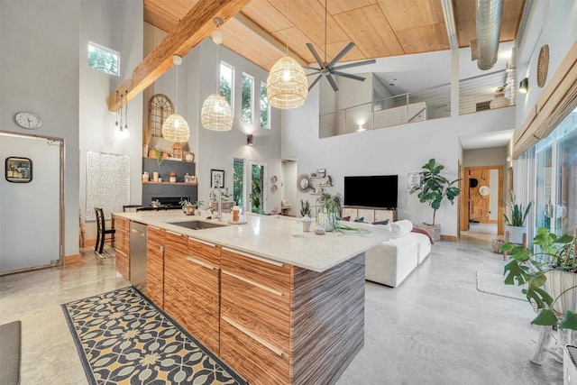 kitchen featuring ceiling fan, dishwasher, sink, a high ceiling, and an island with sink