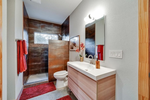 bathroom featuring vanity, toilet, and a tile shower