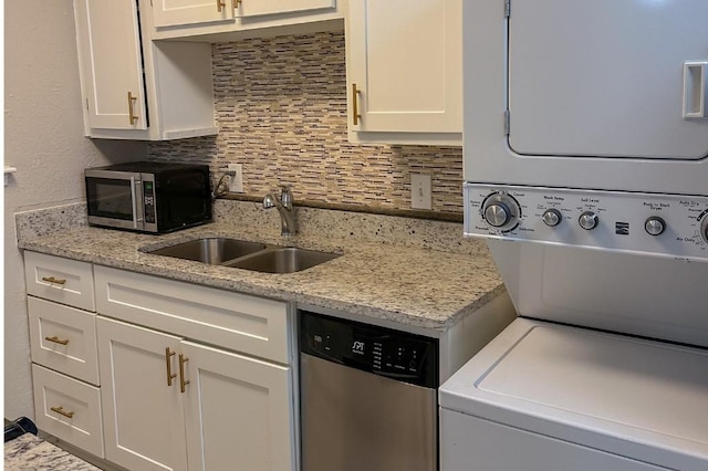 kitchen featuring appliances with stainless steel finishes, white cabinetry, stacked washer / drying machine, and sink