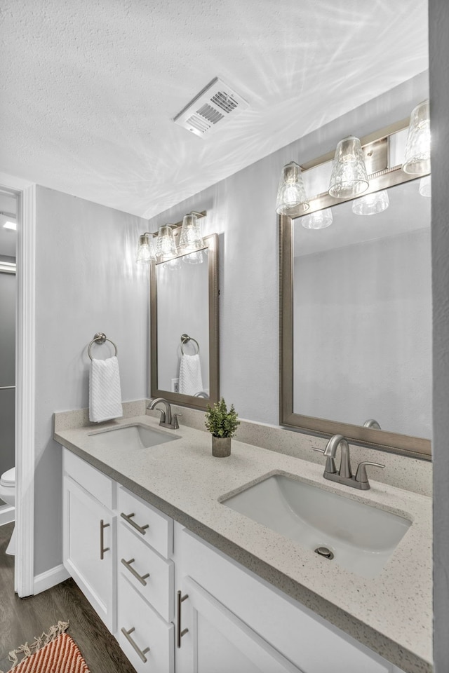 bathroom with hardwood / wood-style floors, vanity, a textured ceiling, and toilet