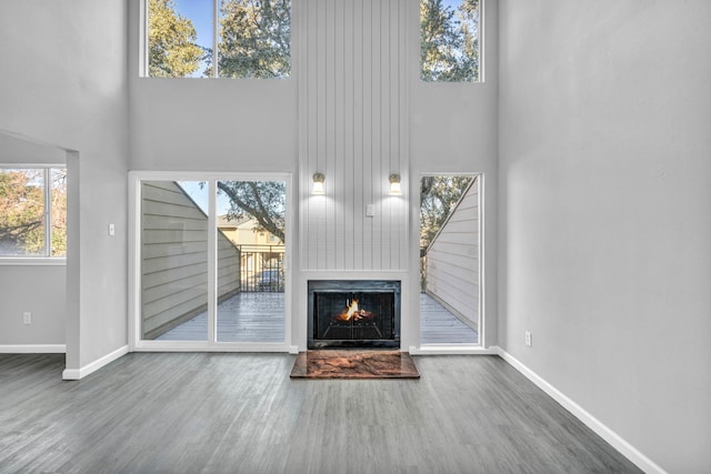 unfurnished living room featuring a towering ceiling and wood-type flooring