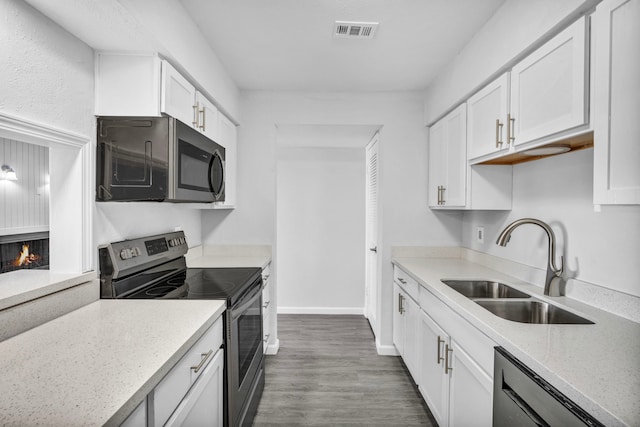 kitchen featuring light stone countertops, appliances with stainless steel finishes, dark wood-type flooring, sink, and white cabinetry