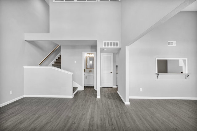 interior space with a towering ceiling, dark hardwood / wood-style flooring, and sink