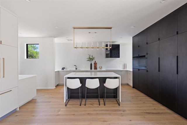 kitchen featuring a kitchen bar, sink, a spacious island, and light hardwood / wood-style flooring