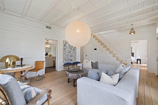 living room featuring beam ceiling, light wood-type flooring, and wood ceiling