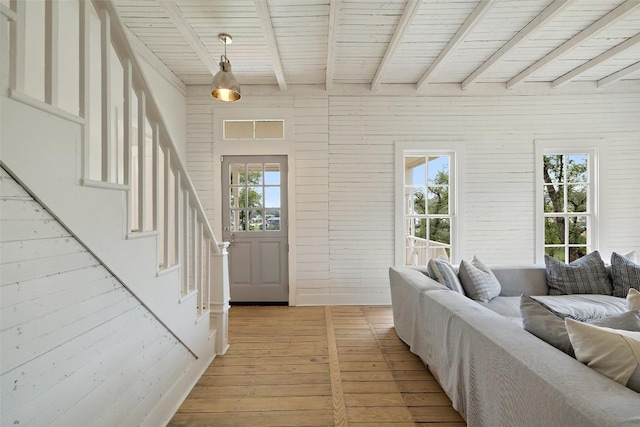 foyer entrance featuring beamed ceiling, light wood-type flooring, wooden ceiling, and wood walls