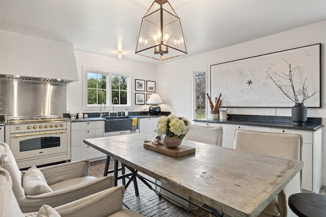 kitchen featuring a chandelier, white cabinets, pendant lighting, and high end white range