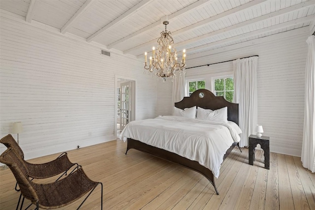 bedroom featuring beamed ceiling, an inviting chandelier, and light hardwood / wood-style flooring