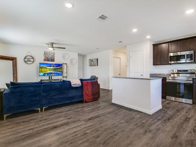 kitchen featuring a center island, dark hardwood / wood-style floors, appliances with stainless steel finishes, dark brown cabinets, and light stone counters