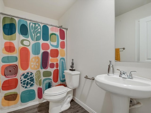 bathroom with a shower with shower curtain, hardwood / wood-style floors, toilet, and sink