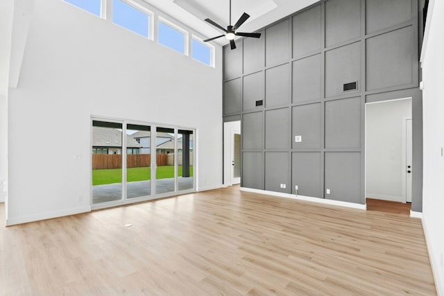 220 Reata Ridge Loop, Liberty Hill, TX 78642 - unfurnished living room with a high ceiling, a decorative wall, ceiling fan, wood finished floors, and baseboards