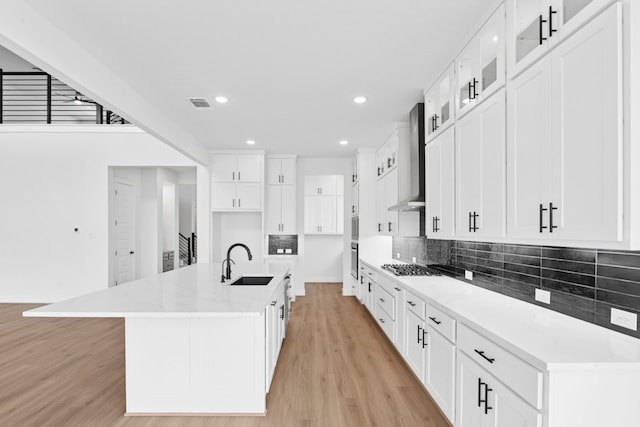220 Reata Ridge Loop, Liberty Hill, TX 78642 - kitchen featuring a sink, wall chimney exhaust hood, light wood finished floors, appliances with stainless steel finishes, and decorative backsplash