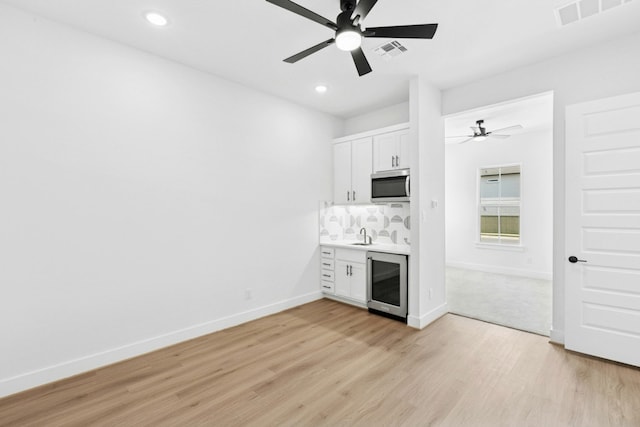 220 Reata Ridge Loop, Liberty Hill, TX 78642 - unfurnished living room with wine cooler, ceiling fan, light wood-type flooring, baseboards, and recessed lighting