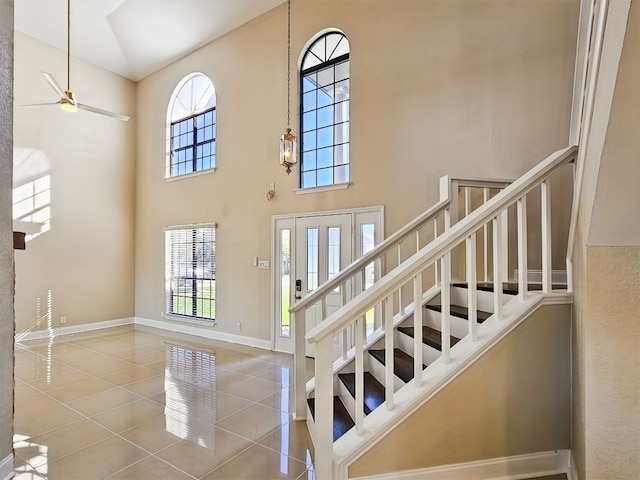 stairway with a towering ceiling and tile patterned flooring