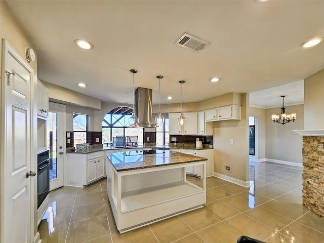 kitchen with island exhaust hood, black appliances, white cabinets, a kitchen island, and decorative light fixtures