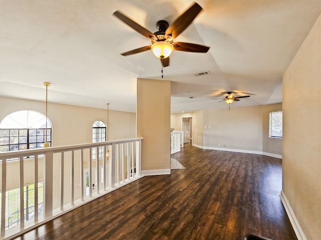 empty room featuring a healthy amount of sunlight, a notable chandelier, and dark hardwood / wood-style flooring