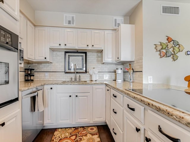 kitchen with white cabinets, tasteful backsplash, dishwasher, and sink