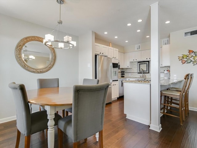 dining space featuring dark hardwood / wood-style floors, sink, and an inviting chandelier