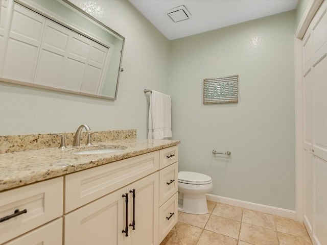 bathroom with toilet, vanity, and tile patterned floors