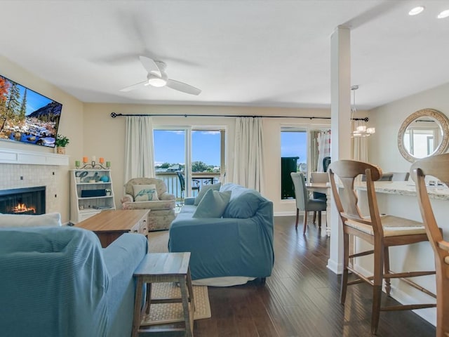 living room featuring a tile fireplace, dark hardwood / wood-style floors, and ceiling fan with notable chandelier