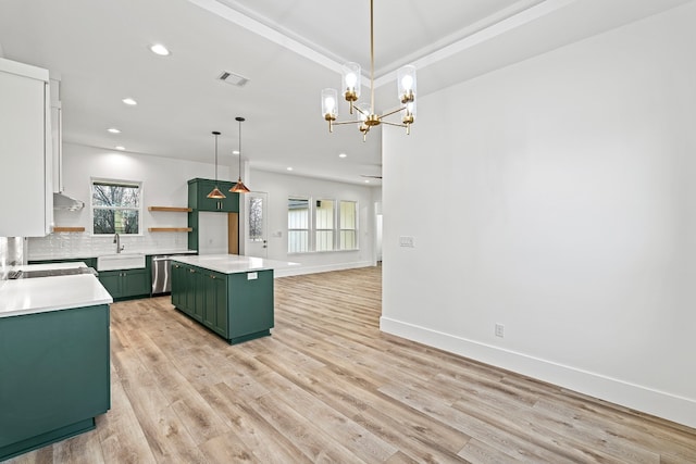 kitchen with a center island, sink, hanging light fixtures, green cabinetry, and decorative backsplash