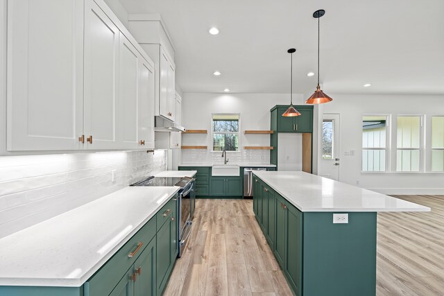 kitchen featuring green cabinets, hanging light fixtures, stainless steel appliances, and sink