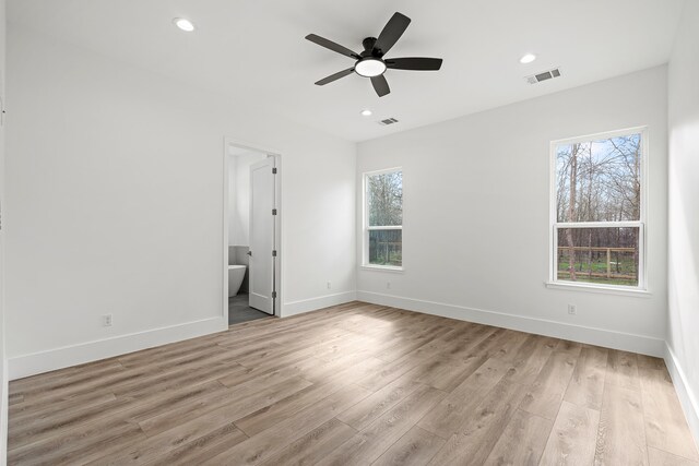 unfurnished bedroom featuring ceiling fan, light hardwood / wood-style flooring, connected bathroom, and multiple windows