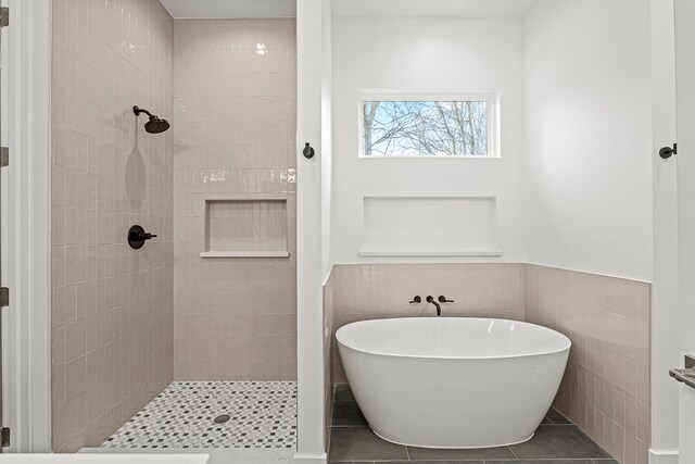 bathroom with plus walk in shower, tile patterned floors, and tile walls