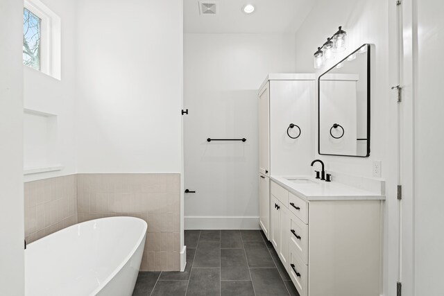 bathroom with a tub to relax in, tile patterned floors, and vanity