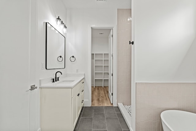 bathroom with tile patterned floors, vanity, tile walls, and independent shower and bath