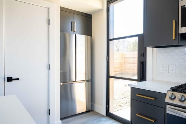 kitchen with decorative backsplash, stainless steel fridge, light wood-type flooring, range, and gray cabinets