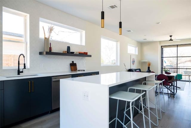 kitchen featuring pendant lighting, sink, stainless steel dishwasher, ceiling fan, and a kitchen island