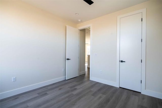 unfurnished bedroom featuring a closet and dark wood-type flooring