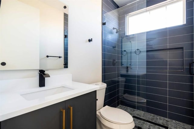 bathroom with tiled shower, vanity, and toilet