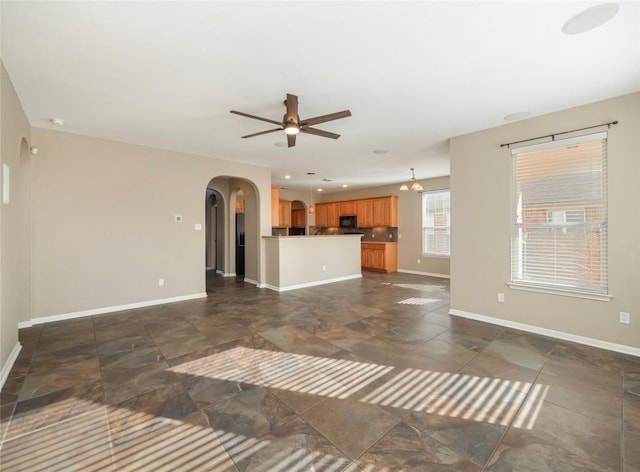 unfurnished living room featuring ceiling fan with notable chandelier