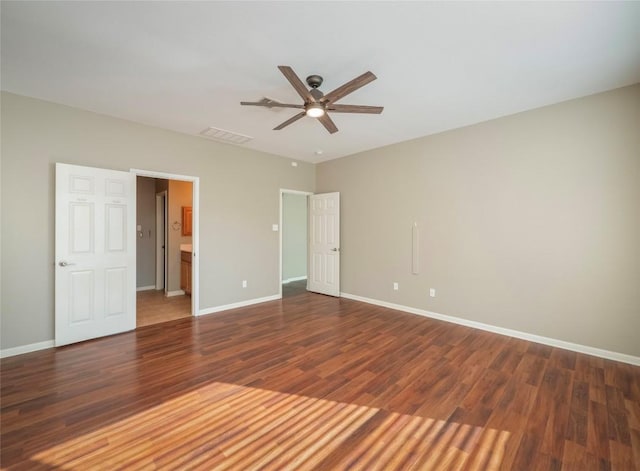 unfurnished bedroom featuring ceiling fan, ensuite bathroom, and dark wood-type flooring