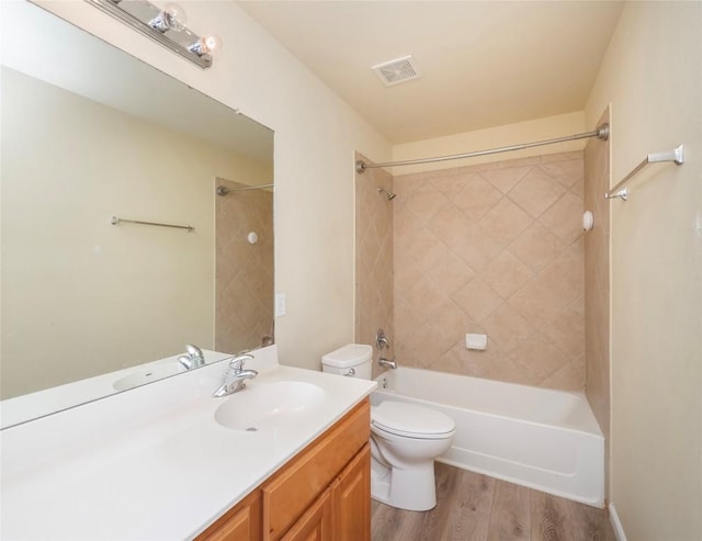 full bathroom featuring hardwood / wood-style floors, tiled shower / bath combo, toilet, and vanity